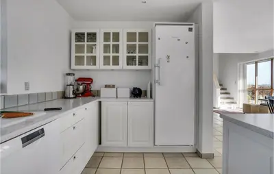 a white kitchen with white cabinets and a refrigerator at Gorgeous Home In Øster Assels in Øster Assels