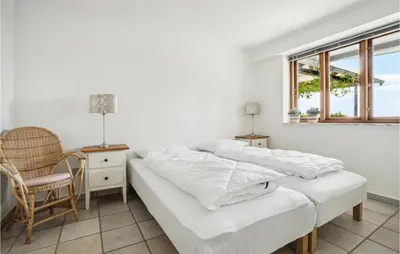 two beds in a room with a chair and a window at Gorgeous Home In Øster Assels in Øster Assels