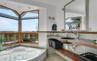 a bathroom with a tub and a sink and two windows at Gorgeous Home In Øster Assels in Øster Assels