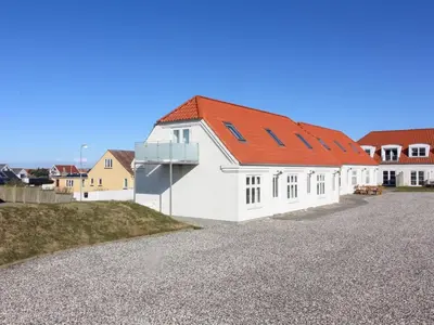 a white building with a red roof on a gravel road at Holiday Home Ena - 75m from the sea by Interhome in Lemvig