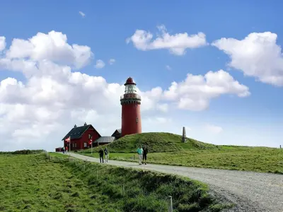 a lighthouse on a hill next to a red house at Holiday Home Ena - 75m from the sea by Interhome in Lemvig