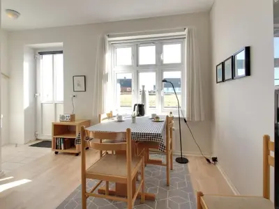 a dining room with a table and chairs and a window at Holiday Home Ena - 75m from the sea by Interhome in Lemvig