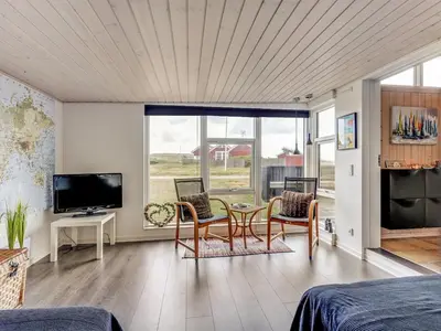a living room with a table and chairs and a tv at Holiday Home Arni - 150m from the sea by Interhome in Lemvig