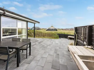 a patio with a wooden table and chairs at Holiday Home Arni - 150m from the sea by Interhome in Lemvig