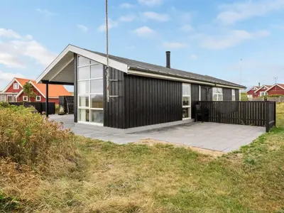 a house with a black facade with a patio at Holiday Home Arni - 150m from the sea by Interhome in Lemvig