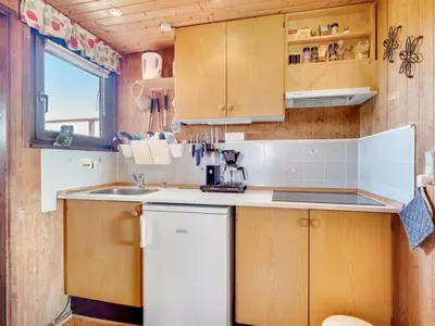 a small kitchen with wooden cabinets and a sink at Holiday Home Beatrice - 150m from the sea by Interhome in Lemvig