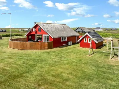 a red house in a field with a playground at Holiday Home Beatrice - 150m from the sea by Interhome in Lemvig