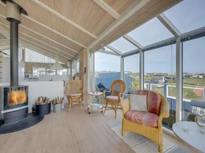 a living room with a fireplace and windows at Holiday Home Rajna - 95m to the fjord by Interhome in Lemvig