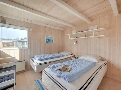 two beds in a room with wooden walls at Holiday Home Rajna - 95m to the fjord by Interhome in Lemvig