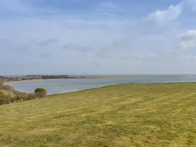 a grassy field with a view of a body of water at Holiday Home Rajna - 95m to the fjord by Interhome in Lemvig