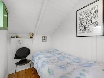 a bedroom with a bed and a chair in it at Holiday Home Kamile - 400m from the sea by Interhome in Harboør