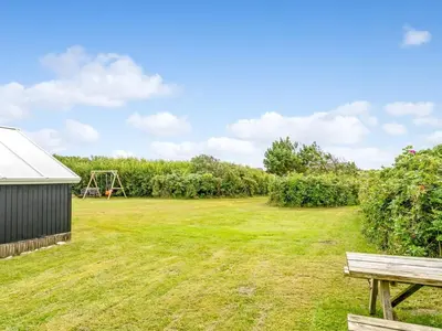 a yard with a bench and a playground at Holiday Home Kamile - 400m from the sea by Interhome in Harboør