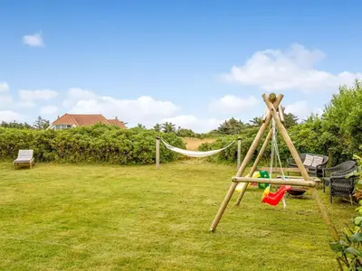 a swing set with a hammock in a yard at Holiday Home Kamile - 400m from the sea by Interhome in Harboør
