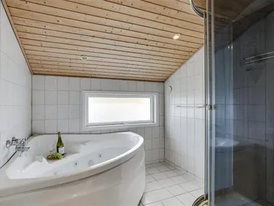 a bathroom with a tub and a shower and a window at Holiday Home Hebba - 300m from the sea by Interhome in Harboør