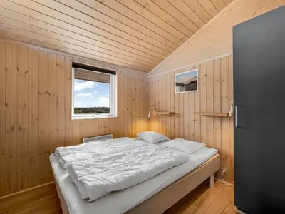 a bedroom with a bed in a wooden room at Holiday Home Floriana - 650m from the sea by Interhome in Harboør