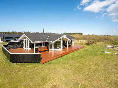 a house with a large deck in a field at Holiday Home Floriana - 650m from the sea by Interhome in Harboør