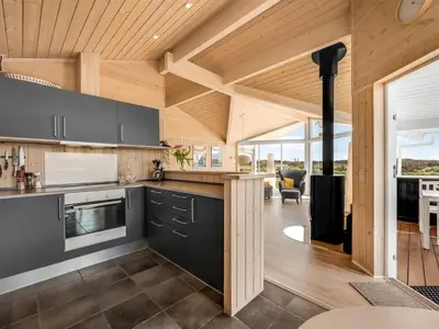 an open kitchen with wooden ceilings and a living room at Holiday Home Floriana - 650m from the sea by Interhome in Harboør