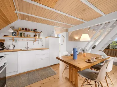 a kitchen with a wooden table and white cabinets at Holiday Home Balthasar - 200m from the sea by Interhome in Harboør