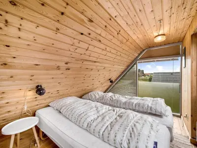 two beds in a room with a wooden wall at Holiday Home Balthasar - 200m from the sea by Interhome in Harboør