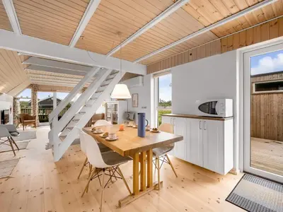 a kitchen and dining room with a wooden table and chairs at Holiday Home Balthasar - 200m from the sea by Interhome in Harboør