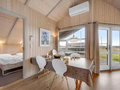 a dining room with a table and chairs and a bed at Holiday Home Mimo - 150m from the sea by Interhome in Harboør