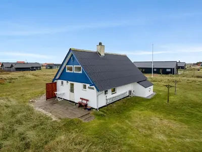 a small house with a blue roof in a field at Holiday Home Eringisl - 50m from the sea by Interhome in Harboør