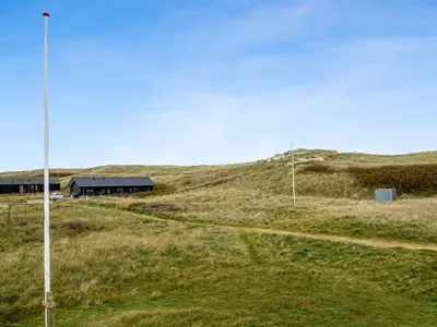 a building in the middle of a grassy field at Holiday Home Eringisl - 50m from the sea by Interhome in Harboør