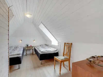 a attic room with two beds and a chair at Holiday Home Pauli - 75m from the sea by Interhome in Harboør