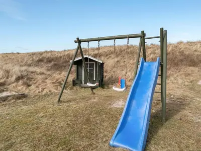 an empty playground with a slide and a swing at Holiday Home Pauli - 75m from the sea by Interhome in Harboør