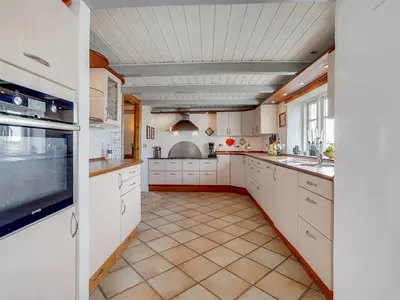 a kitchen with white cabinets and a tile floor at Holiday Home Pauli - 75m from the sea by Interhome in Harboør