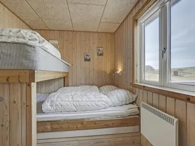 a bunk bed in a wooden room with a window at Holiday Home Hansen - 75m from the sea by Interhome in Harboør
