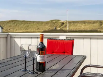 a bottle of wine and two wine glasses on a wooden table at Holiday Home Hansen - 75m from the sea by Interhome in Harboør