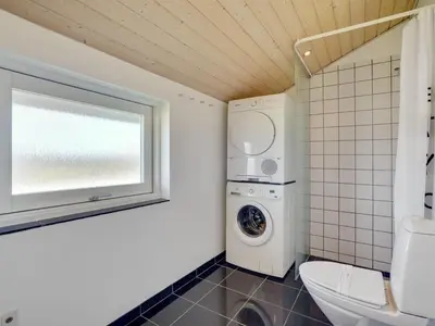 a bathroom with a toilet and a washing machine at Holiday Home Hildegunda - 950m from the sea by Interhome in Harboør