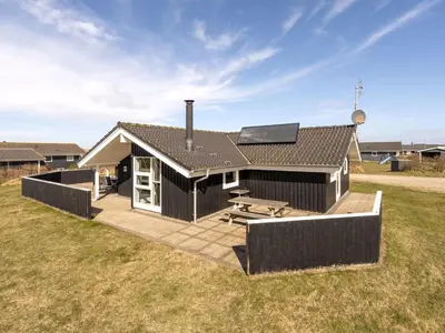 a black house with a deck and a picnic table at Holiday Home Hildegunda - 950m from the sea by Interhome in Harboør