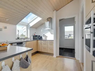a kitchen with a vaulted ceiling and a large window at Holiday Home Hildegunda - 950m from the sea by Interhome in Harboør