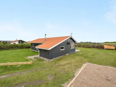 a black house with a red roof in a yard at Holiday Home Thamara - 350m from the sea by Interhome in Harboør