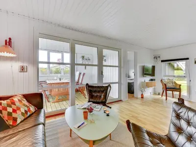 a living room with a table and chairs at Holiday Home Thamara - 350m from the sea by Interhome in Harboør