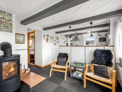 a living room with a fireplace and two chairs at Holiday Home Dietlinde - 100m from the sea by Interhome in Harboør