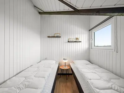 two beds in a white room with a window at Holiday Home Arla - 200m from the sea by Interhome in Harboør