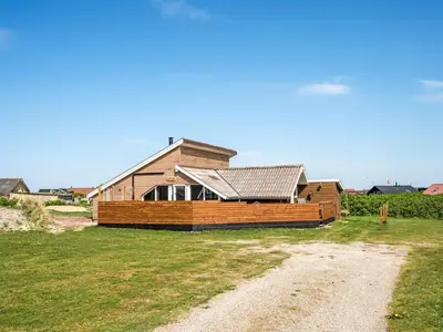 a wooden house on a field with a dirt road at Holiday Home Arla - 200m from the sea by Interhome in Harboør