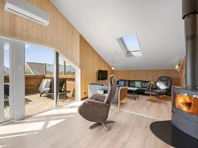 a living room with a chair and a fireplace at Holiday Home Arla - 200m from the sea by Interhome in Harboør