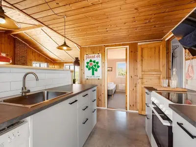 a kitchen with white cabinets and wooden ceilings at Holiday Home Brigit - 200m from the sea by Interhome in Harboør