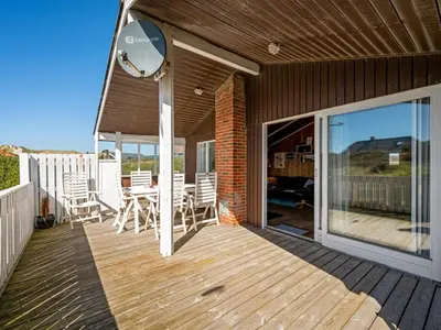 a wooden deck with a table and chairs on it at Holiday Home Brigit - 200m from the sea by Interhome in Harboør