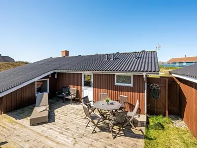 a house with a deck with a table and chairs at Holiday Home Brigit - 200m from the sea by Interhome in Harboør