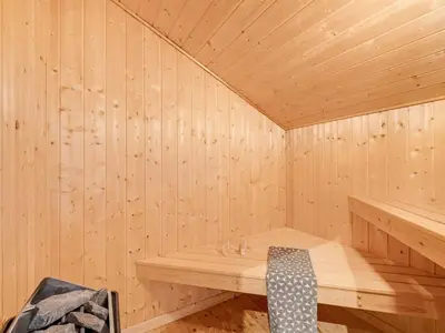 a sauna with a bench in a wooden room at Holiday Home Eemil - 700m from the sea by Interhome in Harboør