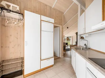 a kitchen with white cabinets and a refrigerator at Holiday Home Eemil - 700m from the sea by Interhome in Harboør