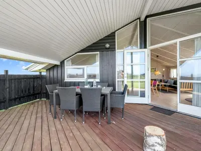 a patio with a table and chairs on a deck at Holiday Home Eemil - 700m from the sea by Interhome in Harboør