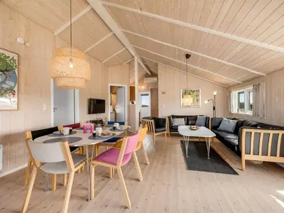 a dining room with a table and chairs and a couch at Holiday Home Eemil - 700m from the sea by Interhome in Harboør