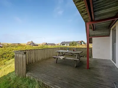a wooden deck with a table and a bench on it at Holiday Home Iines - 200m from the sea by Interhome in Harboør