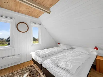 a white bedroom with a bed and two windows at Holiday Home Iines - 200m from the sea by Interhome in Harboør